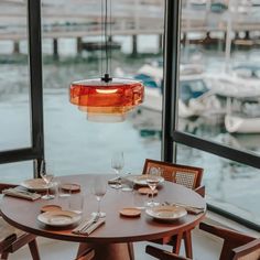 a table with plates and glasses in front of a large window overlooking the water's boats