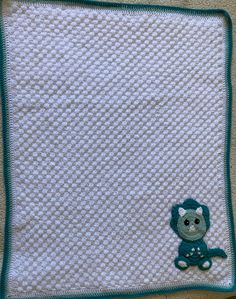 a crocheted baby blanket with a teddy bear on the front and blue trim