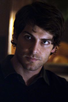 a close up of a person wearing a black shirt and looking at the camera with a serious look on his face