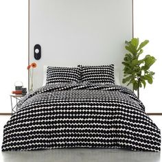 a bed with black and white bedspread next to a potted green plant