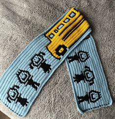 two blue and yellow knitted bookmarks with school bus on them sitting on top of a gray blanket