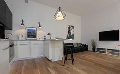 a living room and kitchen area with white walls, hardwood floors and an island in the middle