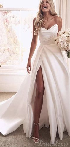 a woman in a white dress is smiling and posing for the camera while holding a bouquet