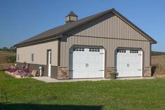 two garages in the middle of a field with flowers on each side and one door open