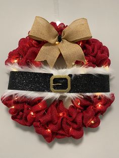 a christmas wreath with lights on it and a bow hanging from the front of it