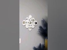 there is a clock on the wall with feathers around it and two vases in front