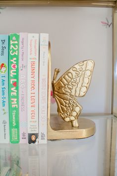 a book shelf with books and a butterfly figurine