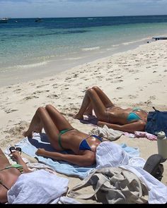 two women in bikinis laying on the beach