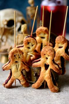 some food is on sticks in the shape of people and bones with toothpicks sticking out of them