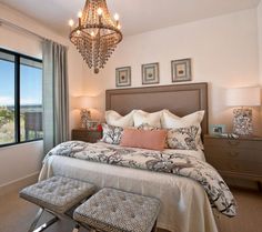 a bedroom with a chandelier hanging from the ceiling and a bed in front of a large window