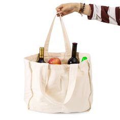 a person holding a tote bag full of wine bottles and an apple in it