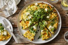 an omelet with cheese and greens on a plate next to silverware, forks and glasses