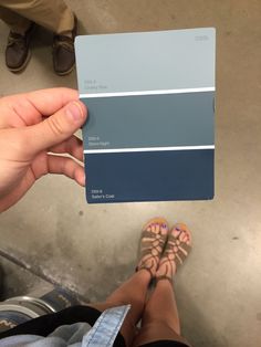 a person holding up a blue and gray color swatch in front of their feet