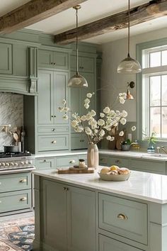 a kitchen with green cabinets and marble counter tops, white flowers in a vase on the island