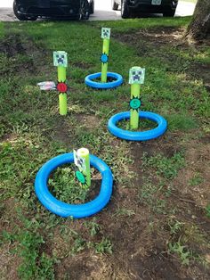 some blue and green plastic rings in the grass near a car parked on the side of the road