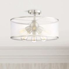 a white ceiling light hanging from the ceiling in a room with beige walls and curtains