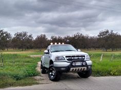 the truck is parked on the side of the road in front of some grass and trees