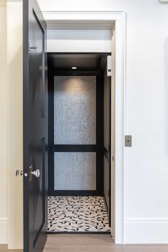 an open door leading to a bathroom with black and white floor tiles on the floor