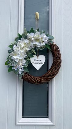 a heart shaped wreath with flowers on the front door