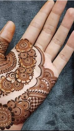 a woman's hand with henna on it and a cell phone in the background