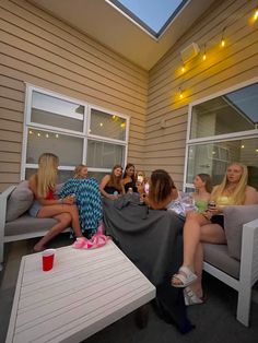 a group of women sitting on top of couches in front of a house at night