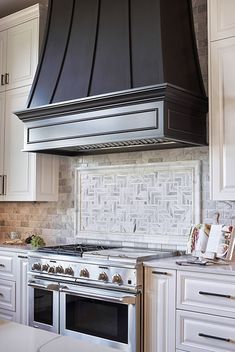 a stove top oven sitting inside of a kitchen next to white cabinets and counter tops