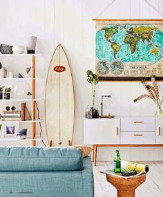 a living room filled with furniture and a surfboard on top of a shelf in front of a wall