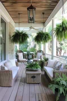 a porch with wicker furniture and potted plants hanging from the ceiling over it