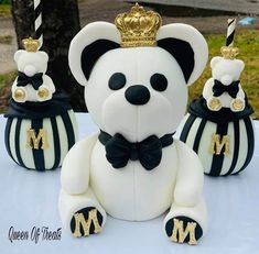 a white teddy bear sitting on top of a table next to two black and white striped pumpkins