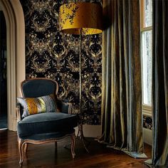 a chair sitting in front of a window next to a lamp on a wooden floor