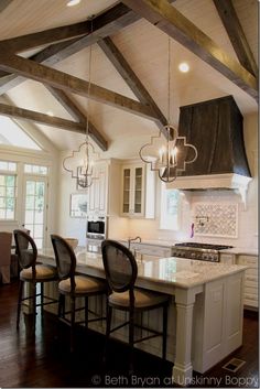 an instagramted photo of a kitchen with white cabinets and wood beams on the ceiling