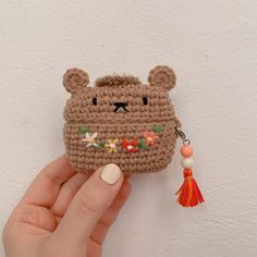 a hand holding a small crocheted bear purse with tassels on it