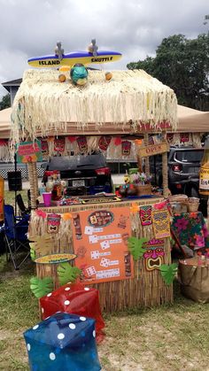 an outdoor food stand with umbrellas and decorations on the grass, under a cloudy sky