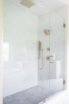 a bathroom with a glass shower door and gold fixtures on the wall next to it