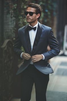 a man in a tuxedo is walking down the street with his hands on his hips