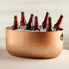 a metal bowl filled with beer bottles on top of a table