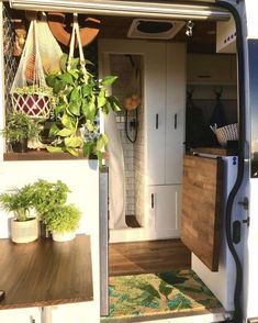 the interior of a camper van with potted plants and hanging baskets on the door