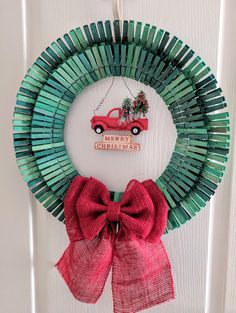 a christmas wreath with a red truck and bow hanging on the front door, made out of popsicle sticks