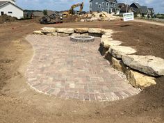 a brick patio being built in the middle of a construction site with large rocks surrounding it