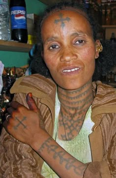 a woman with tattoos on her arm and chest sitting at a table in a bar