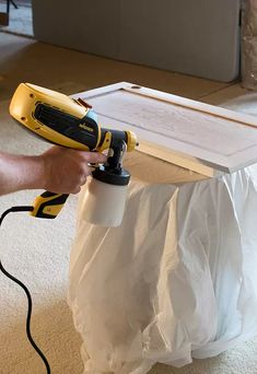 a person using a power drill to paint a piece of furniture