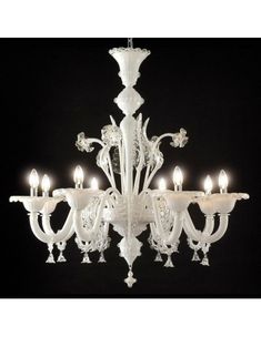 a white chandelier with many lights on it's sides and four candles in the middle