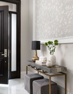 a table with two stools in front of it and a vase on the side