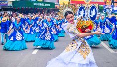 a group of women in blue and white dresses are marching down the street with colorful costumes