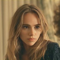 a close up of a person with long hair wearing a black shirt and looking at the camera