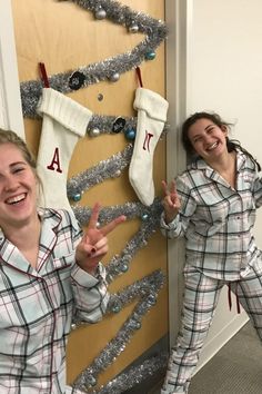 two women dressed in pajamas posing for the camera with christmas stockings hanging up behind them