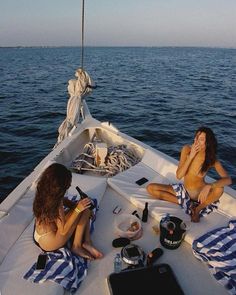 two women are sitting on the back of a boat in the water while one woman brushes her teeth