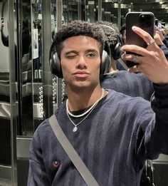 a man wearing headphones taking a selfie in front of a mirror with his cell phone