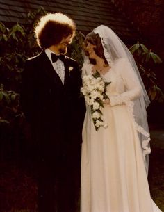 a man and woman dressed in wedding attire standing next to each other on their wedding day