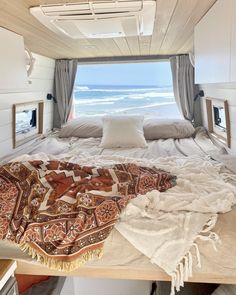 a camper - van interior is shown with the bed covered in blankets and pillows